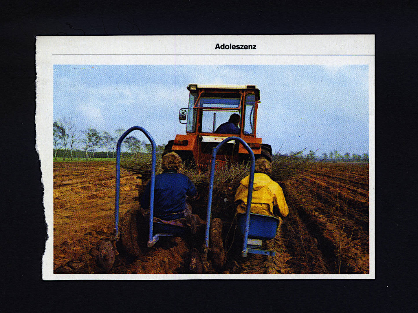 cut out page of a printed lexicon book, the page for Adolescence. theres a picture of two people sitting on a farming device behind a truck on a field doing farm work.